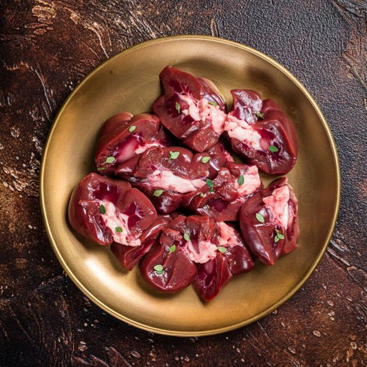 Raw beef kidney pieces on a gold plate with a dark background